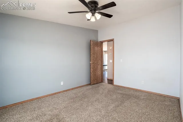 an empty room with closet and a chandelier fan
