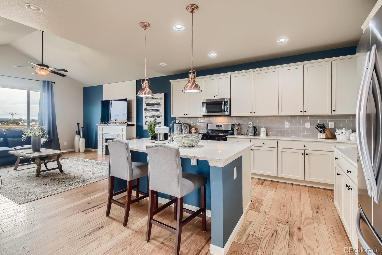16035 Newark Lane Brighton, CO 80602 - Photo 11 of 40 a kitchen with kitchen island granite countertop a sink a stove a refrigerator cabinets and chairs