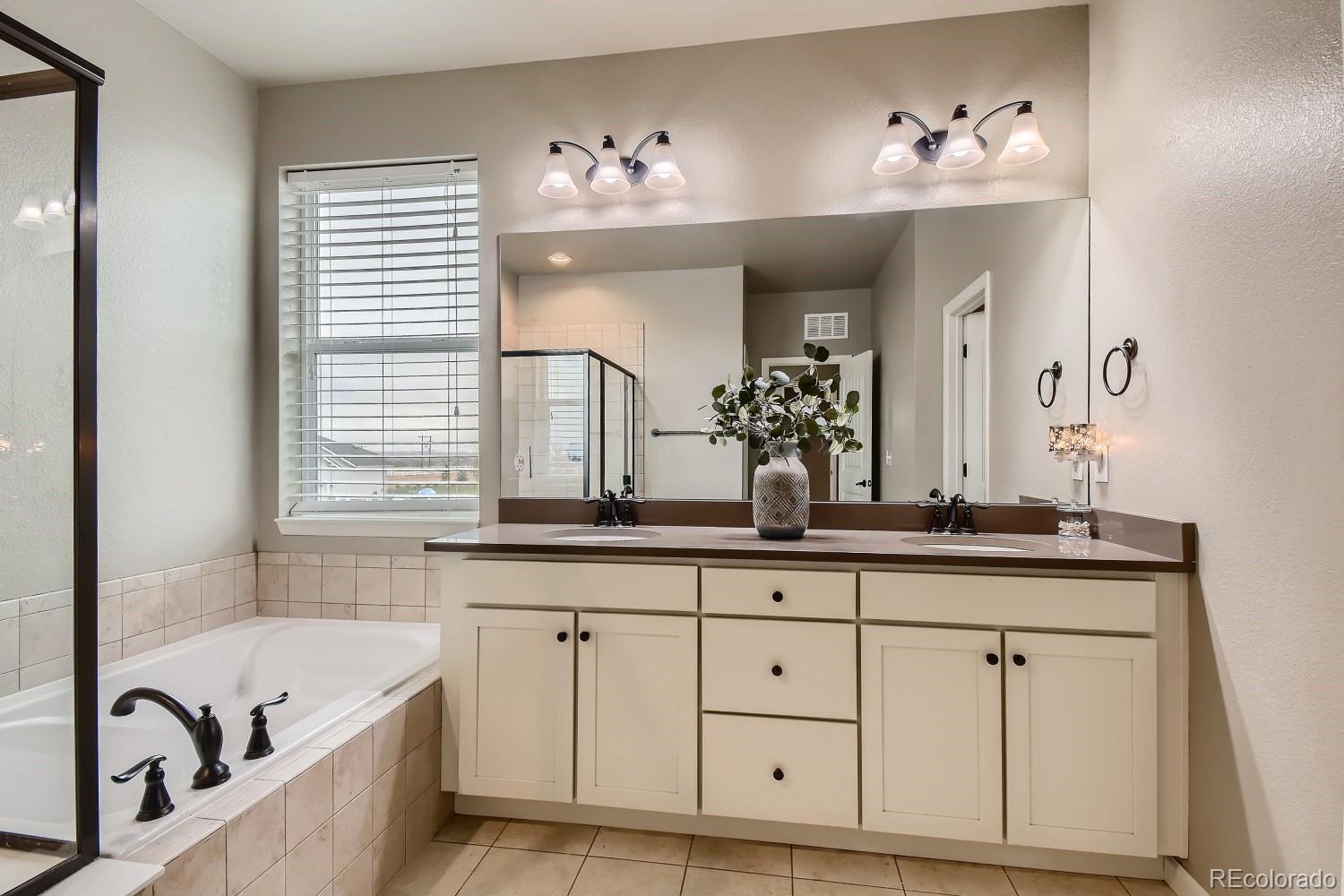 16035 Newark Lane Brighton, CO 80602 - Photo 21 of 40 a bath room with double vanity sink a mirror and a bathtub
