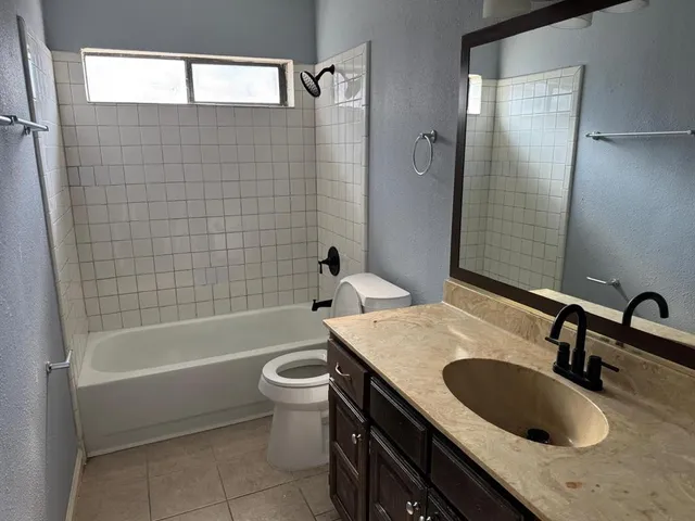 a bathroom with a granite countertop sink a toilet and bathtub