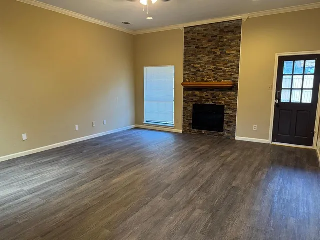 an empty room with wooden floor fireplace and windows
