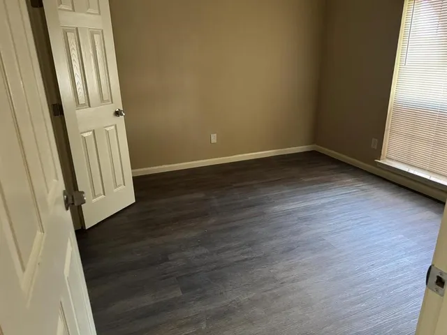 an empty room with wooden floor and entrance