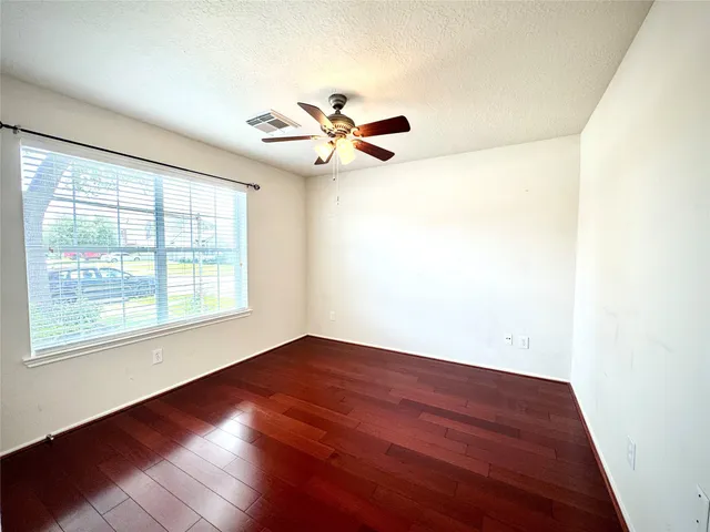 an empty room with wooden floor fan and windows