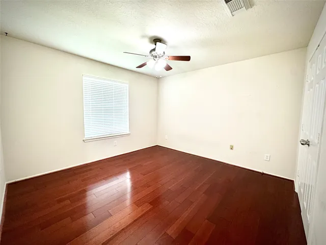 an empty room with wooden floor fan and windows
