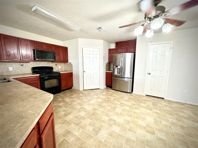 a large kitchen with cabinets stove top oven and stainless steel appliances