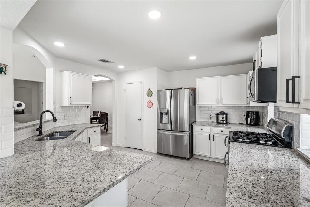1011 Ridgecrest Drive McKinney, TX 75069 - Photo 13 of 31 Kitchen featuring granite countertops, white cabinetry with dark hardware, stainless steel appliances, and tile flooring