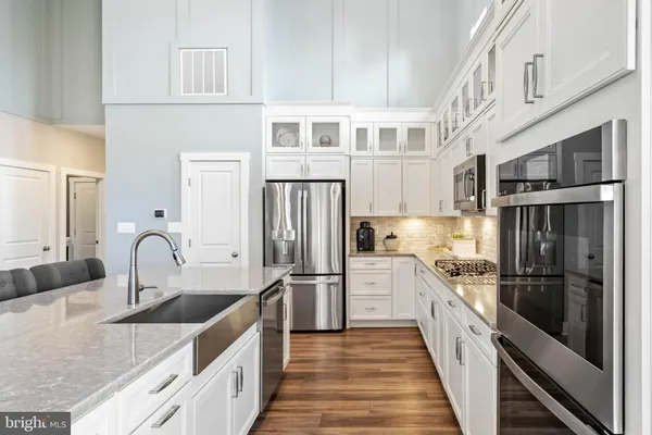 a view of kitchen with granite countertop a table chairs sink and wooden floor