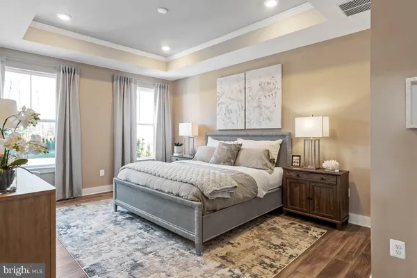 a bedroom with a bed potted plant on dresser and a window
