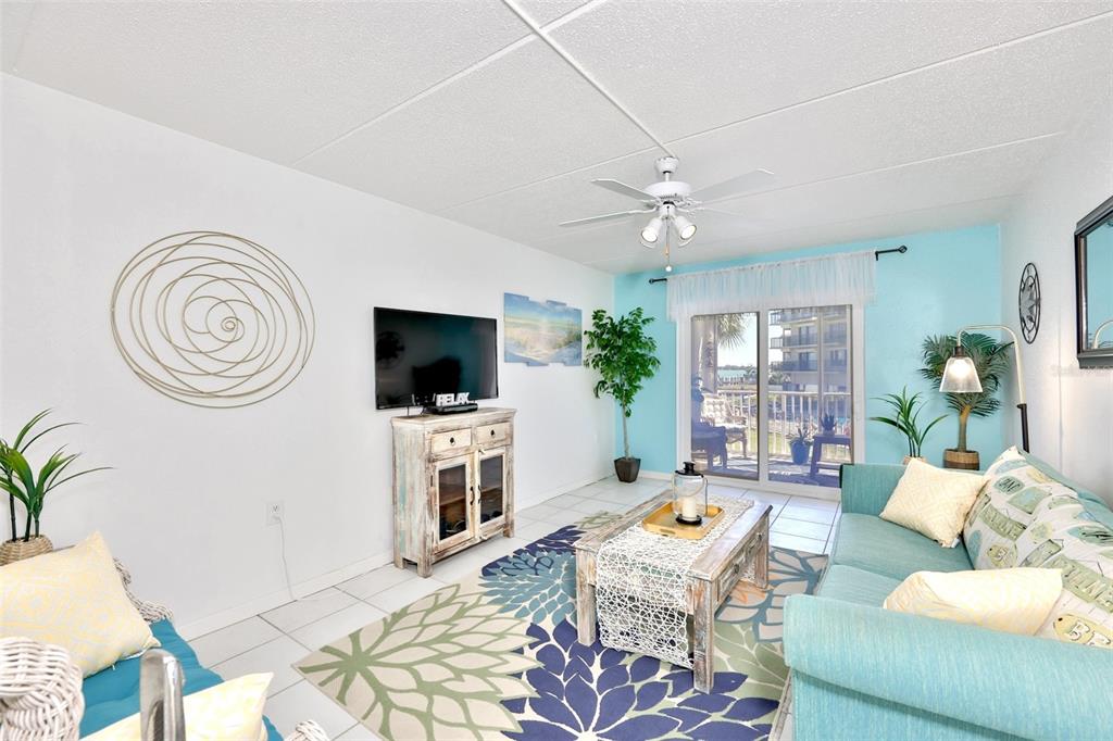 8901 Blind Pass Road, Unit 224 St. Pete Beach, FL 33706 - Photo 16 of 46 a living room with furniture a flat screen tv and a window