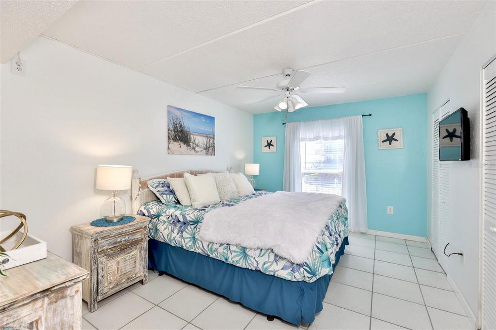 8901 Blind Pass Road, Unit 224 St. Pete Beach, FL 33706 - Photo 21 of 46 a bedroom with a bed and a chandelier