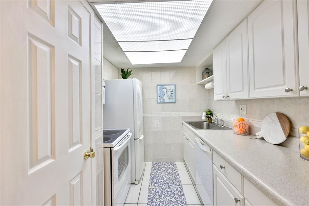 8901 Blind Pass Road, Unit 224 St. Pete Beach, FL 33706 - Photo 9 of 46 a kitchen with a sink a refrigerator and cabinets