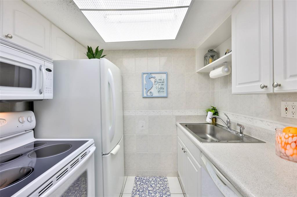 8901 Blind Pass Road, Unit 224 St. Pete Beach, FL 33706 - Photo 10 of 46 a kitchen with stainless steel appliances granite countertop a sink and a refrigerator