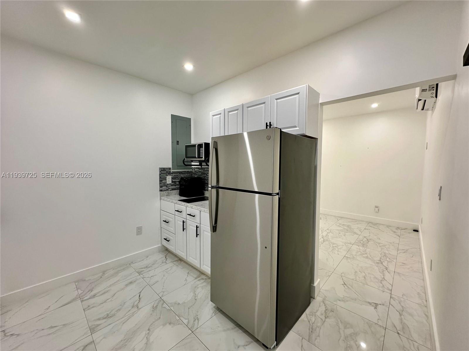 1309 Northwest 55th Terrace, Unit STUDIO Miami, FL 33142 - Photo 3 of 18 a kitchen with a refrigerator and white cabinets