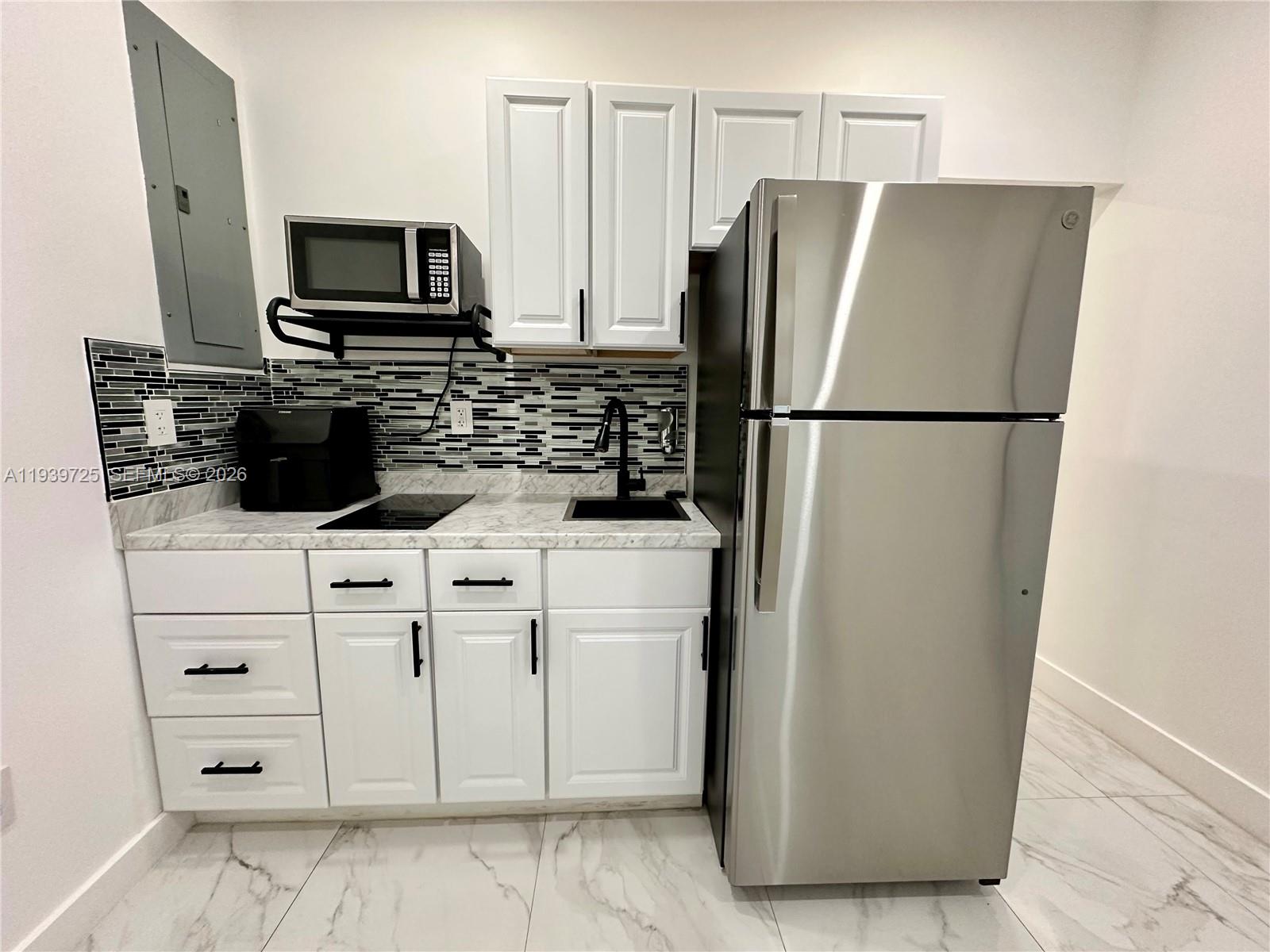 1309 Northwest 55th Terrace, Unit STUDIO Miami, FL 33142 - Photo 4 of 18 a white refrigerator freezer and a stove sitting inside of a kitchen