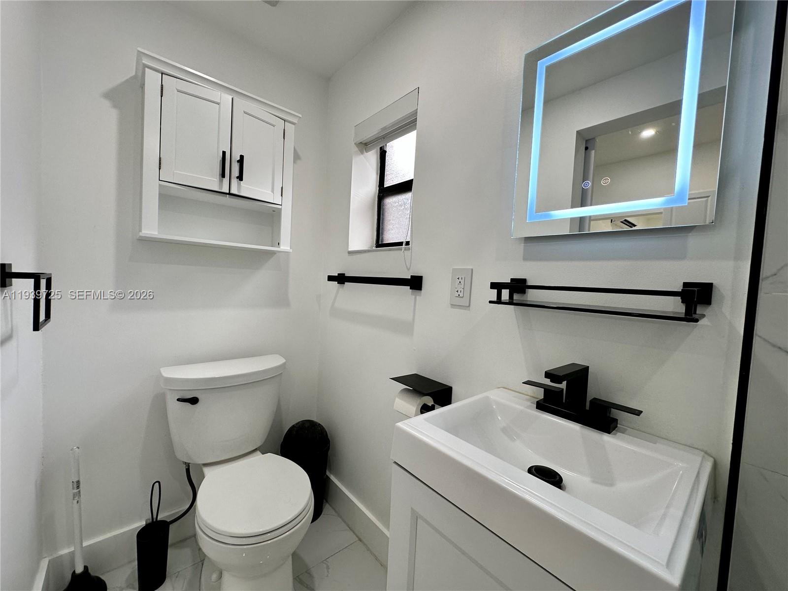 1309 Northwest 55th Terrace, Unit STUDIO Miami, FL 33142 - Photo 6 of 18 a bathroom with a sink a toilet and a mirror