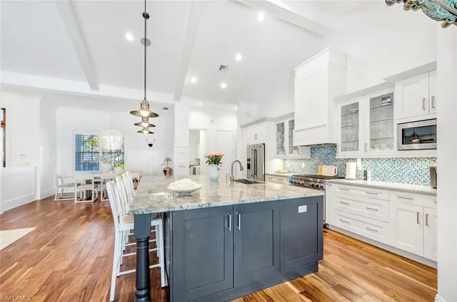 a kitchen with stainless steel appliances kitchen island granite countertop a stove a sink and white cabinets with wooden floor