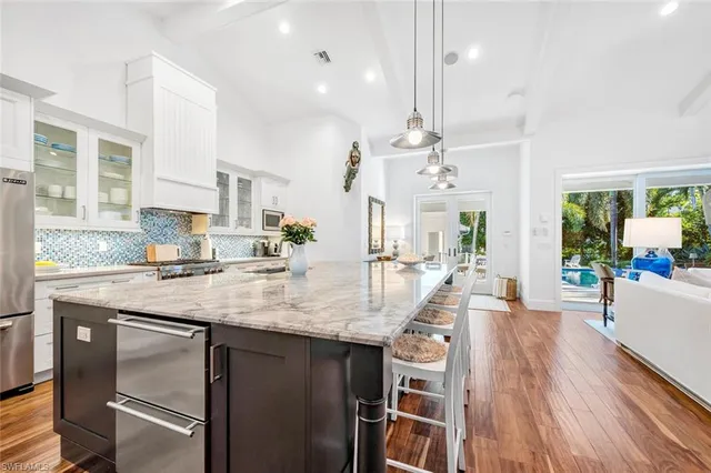 a kitchen with kitchen island a large counter top space a sink stainless steel appliances and cabinets