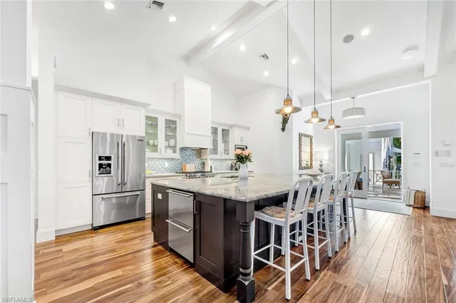 a kitchen with stainless steel appliances kitchen island granite countertop a table chairs and a refrigerator