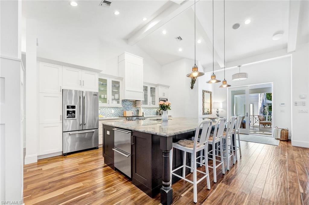 Undisclosed Address Naples, FL 34102 - Photo 19 of 44 a kitchen with stainless steel appliances kitchen island granite countertop a table chairs and a refrigerator