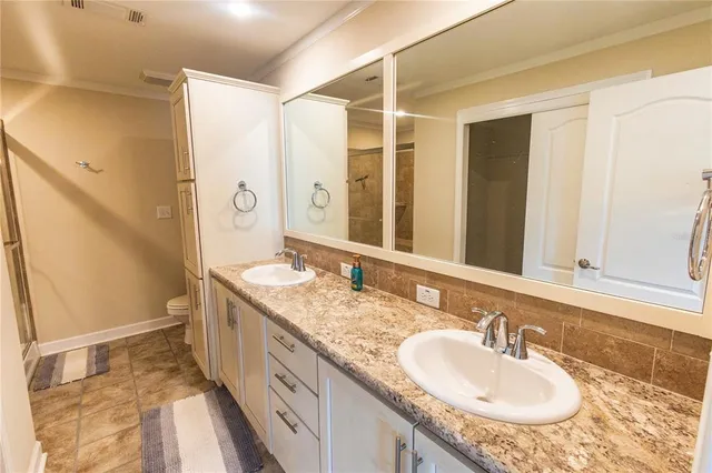 a bathroom with a granite countertop double vanity sink and mirror