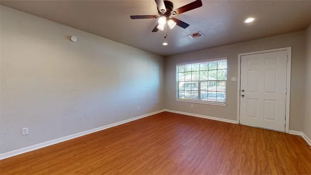 a view of an empty room with wooden floor and a window