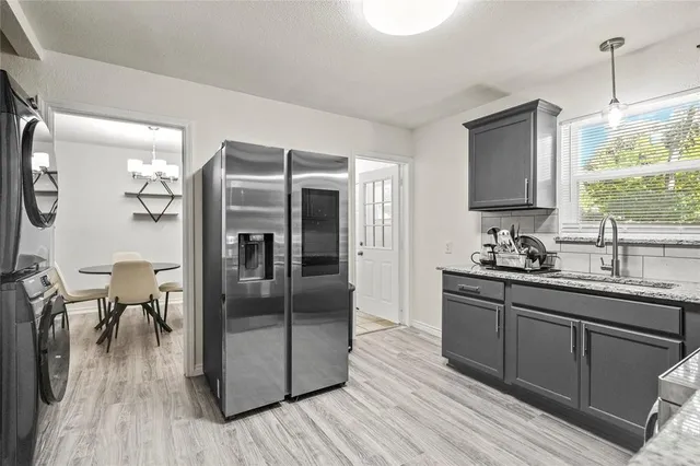 a kitchen with stainless steel appliances granite countertop a refrigerator a sink dishwasher a stove and white countertops with wooden floor