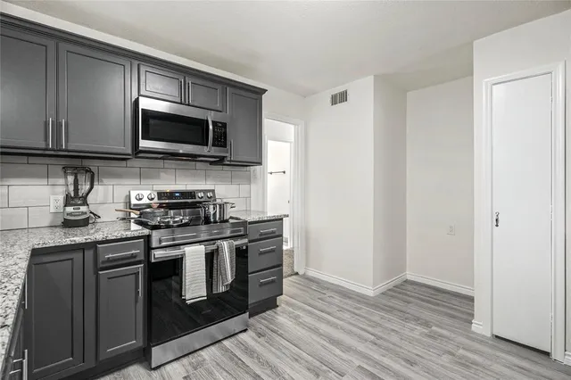 a kitchen with stainless steel appliances granite countertop a stove a microwave and a sink