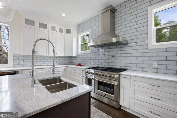 a kitchen with stainless steel appliances granite countertop a stove a sink and a white wooden cabinets