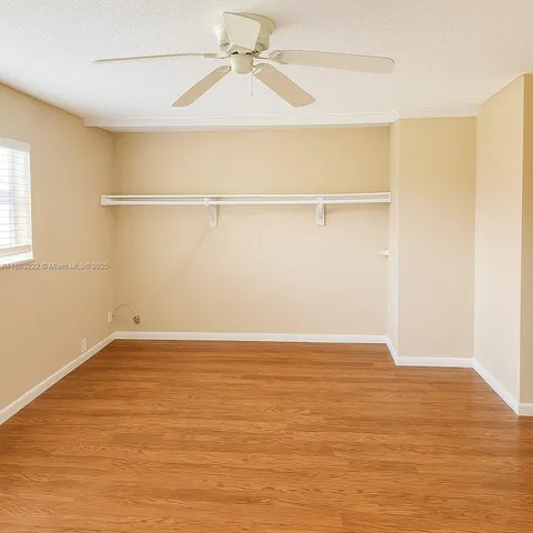an empty room with wooden floor closet and windows