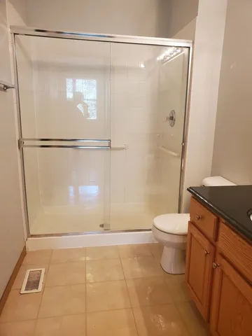 a bathroom with a granite countertop sink toilet a mirror a shower and a vanity