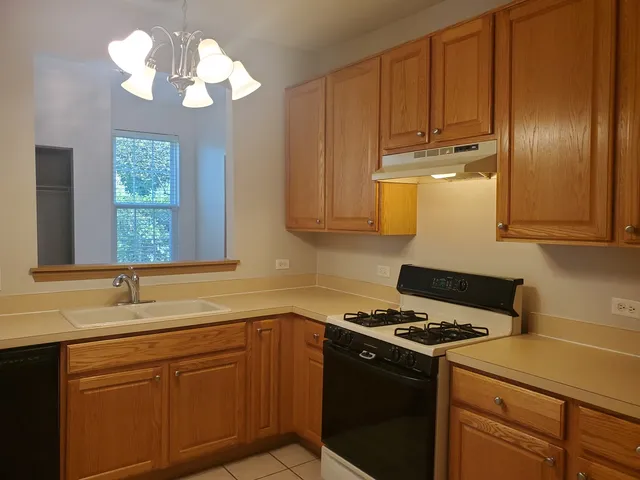 a kitchen with stainless steel appliances a stove a sink cabinets and a window