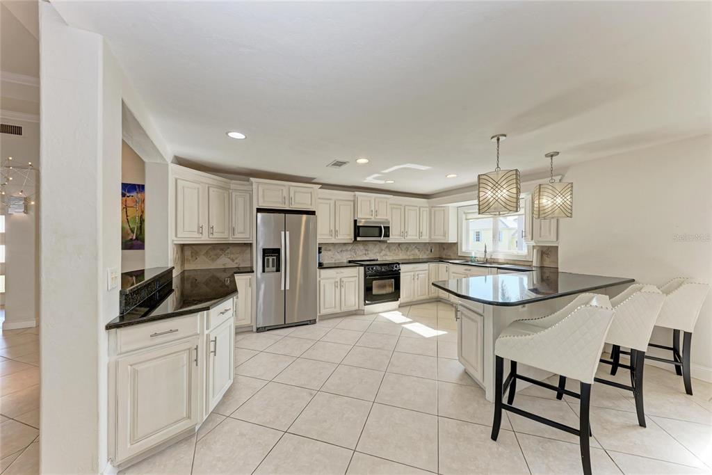 3291 Bayou Road Longboat Key, FL 34228 - Photo 7 of 41 a kitchen with white cabinets and stainless steel appliances