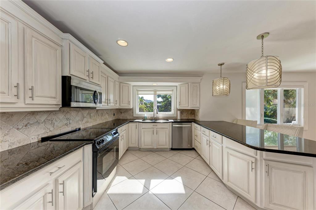 3291 Bayou Road Longboat Key, FL 34228 - Photo 8 of 41 a large kitchen with stainless steel appliances granite countertop a sink and white cabinets
