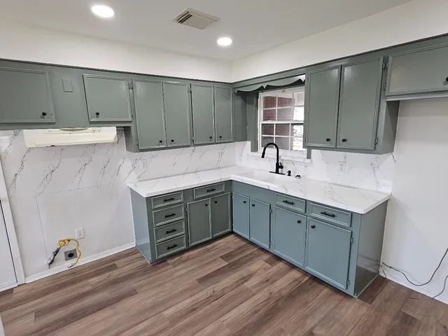 a kitchen with a sink cabinets and wooden floor