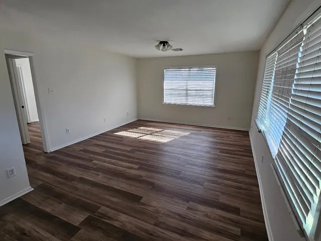 a view of an empty room with wooden floor and a window