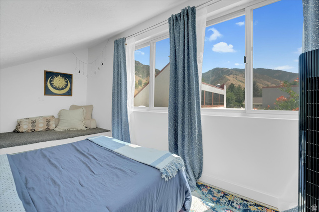 510 Spring Creek Road Providence, UT 84332 - Photo 21 of 97 Room featuring multiple windows, a mountain backdrop, an angled ceiling, a built-in bench, and wood-finish flooring