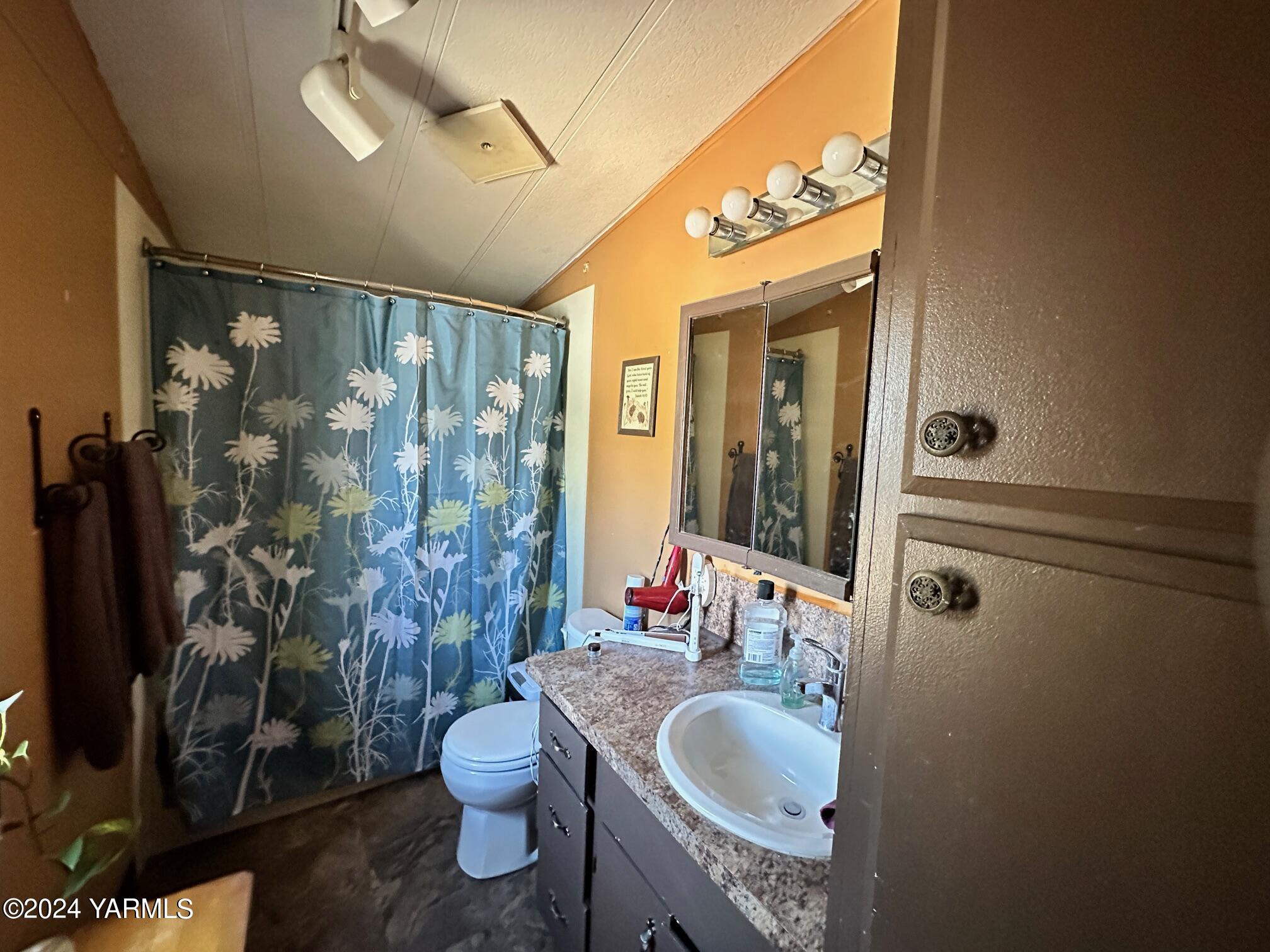 1131 County Line Road Grandview, WA 98930 - Photo 7 of 11 a bathroom with a granite countertop sink toilet a mirror and shower