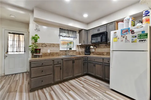 a kitchen with stainless steel appliances granite countertop a refrigerator sink and wooden cabinets