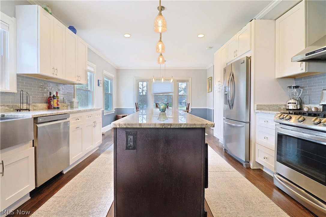 4376 Dover Center Road North Olmsted, OH 44070 - Photo 13 of 34 Kitchen featuring appliances with stainless steel finishes, pendant lighting, a kitchen island, backsplash, and dark hardwood / wood-style floors