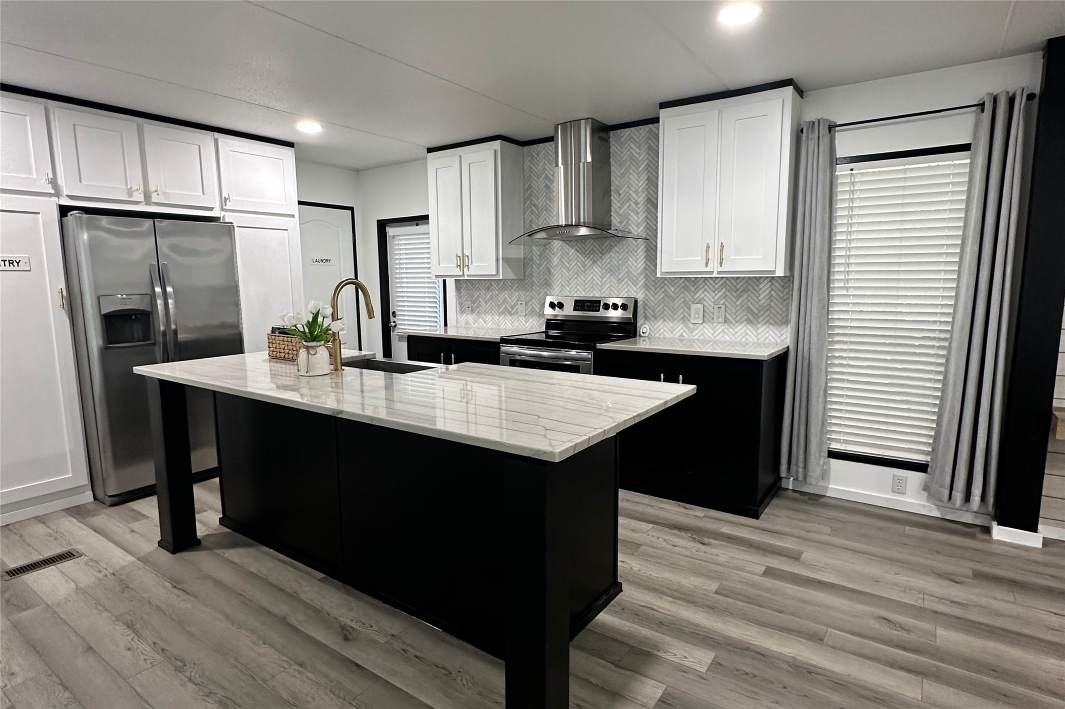 1601 East Slaughter Lane, Unit 464 Austin, TX 78747 - Photo 1 of 26 Kitchen featuring stainless steel appliances, two tone color scheme, light stone countertops, a kitchen island with sink, and light wood-style floors