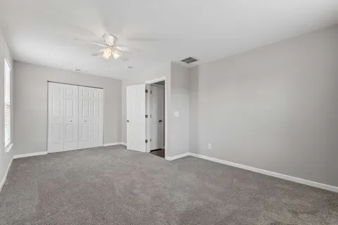 a view of an empty room and a chandelier fan