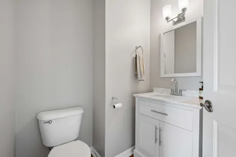 a bathroom with a toilet sink vanity and mirror