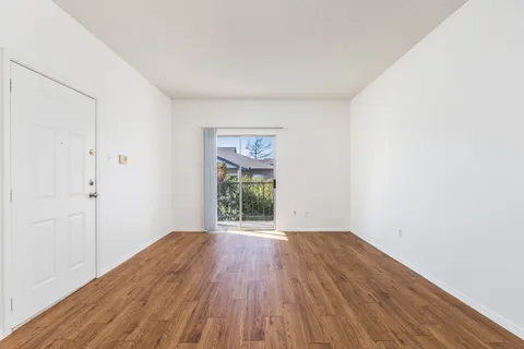 a view of an empty room with wooden floor and a window