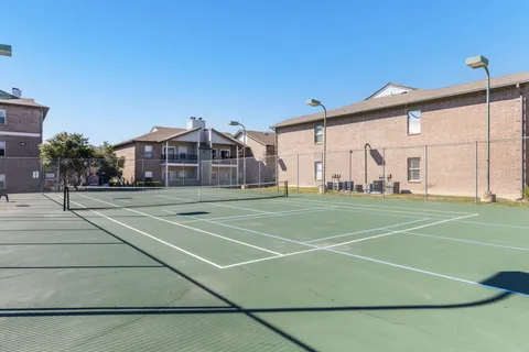 a view of a tennis ground with large trees