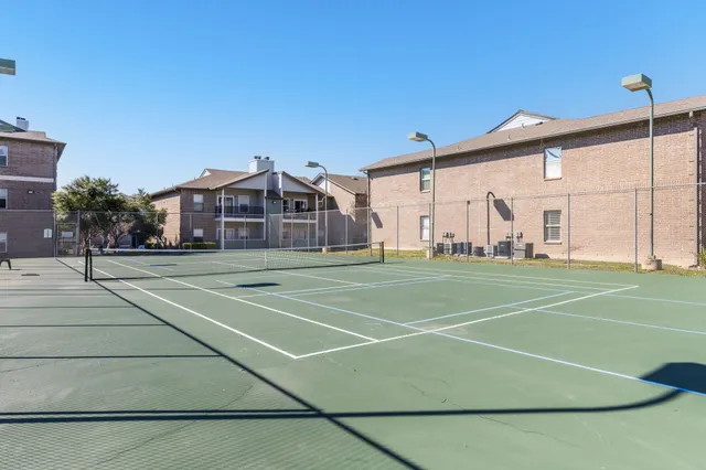 a view of a tennis ground with large trees
