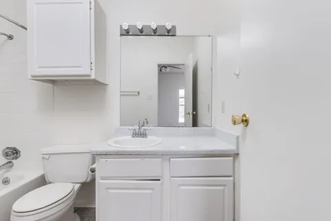 a bathroom with a sink vanity granite toilet and a mirror