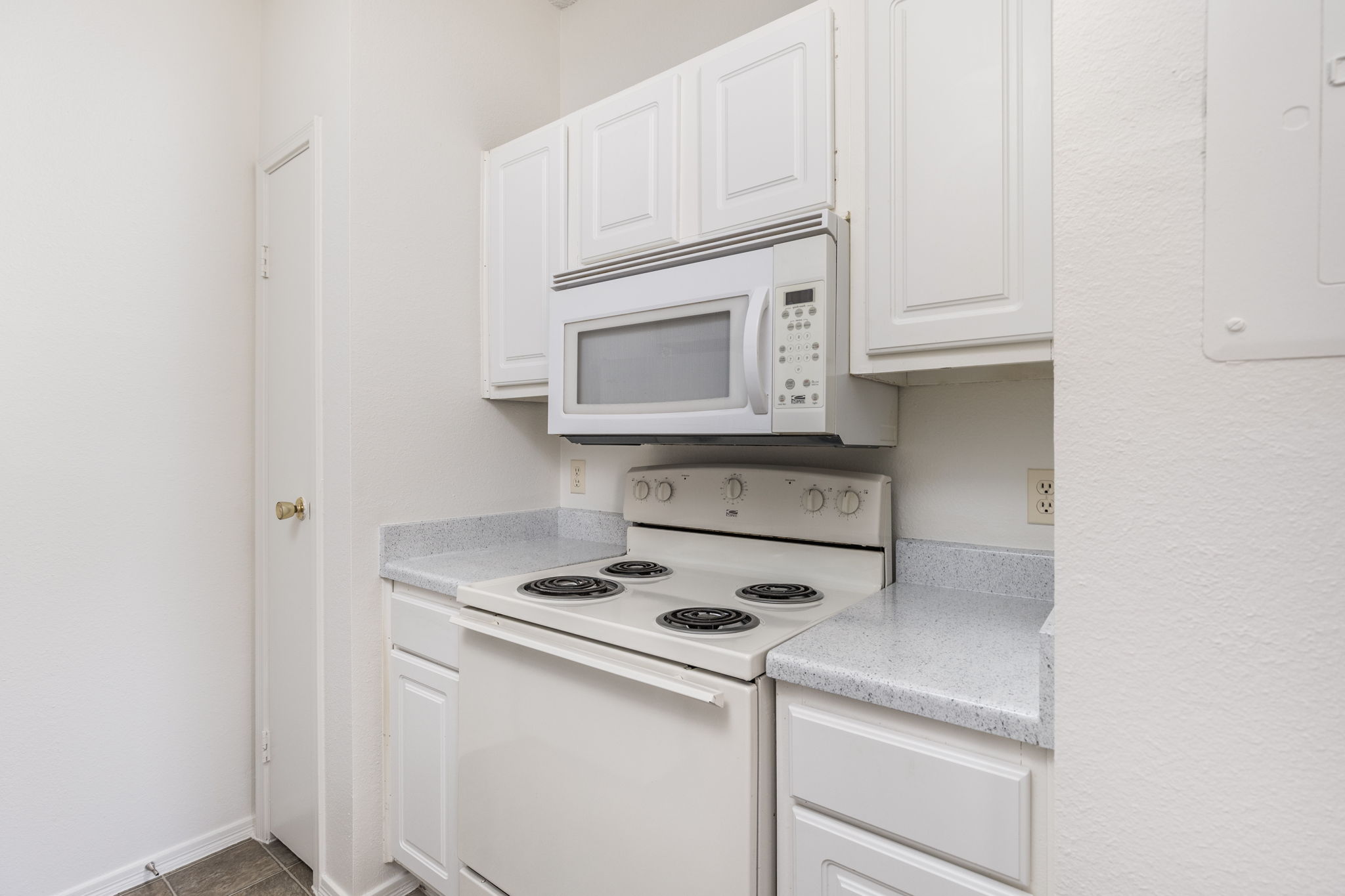 12166 Metric Boulevard, Unit 230 Austin, TX 78758 - Photo 6 of 32 a kitchen with white cabinets and white appliances