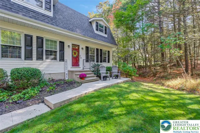 a view of a house with a big yard plants and large trees
