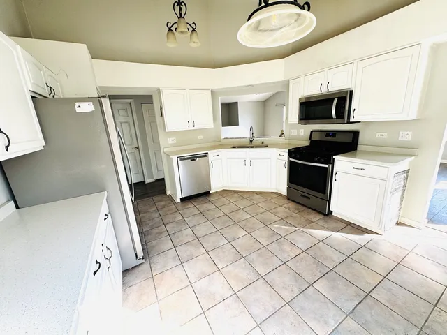 a large white kitchen with a sink stainless steel appliances and cabinets