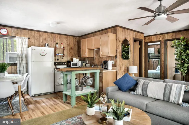 a living room with stainless steel appliances furniture a rug and a large window